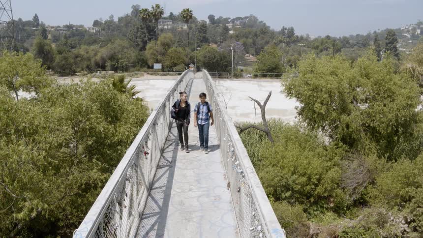 People walking over a bridge surrounded by trees