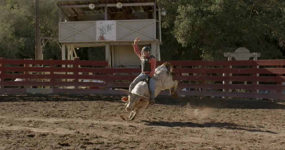 A cowboy rides a bull on a ranch