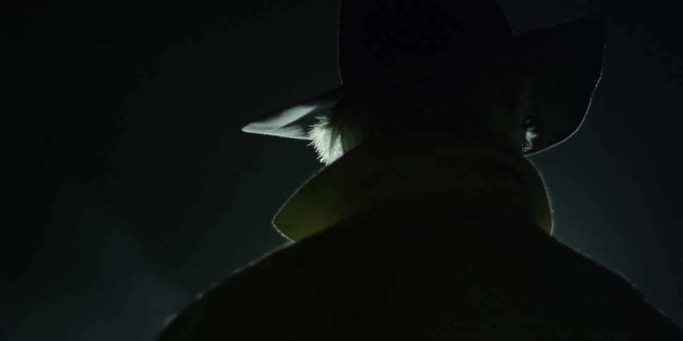 A man in a cowboy hat watches a front loader drive by at night
