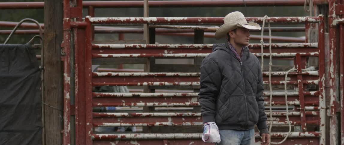 Cowboy standing in a corral with one hand bandaged up