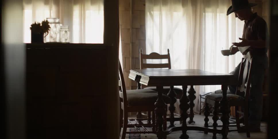 A cowboy sits down at a dining room table with food