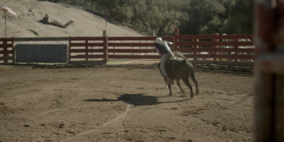 A cowboy rides a bull on a ranch