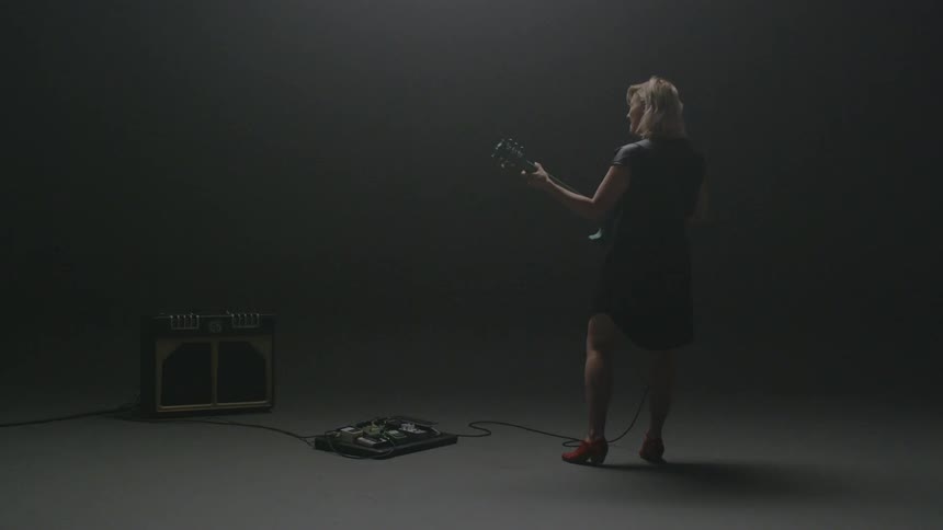 A woman is playing the guitar in the dark room