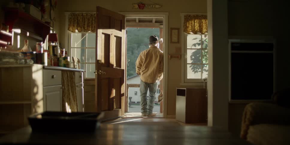 A cowboy leans in a front doorway