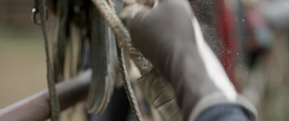 Gloved person grasping and pulling on a rope as material powders off