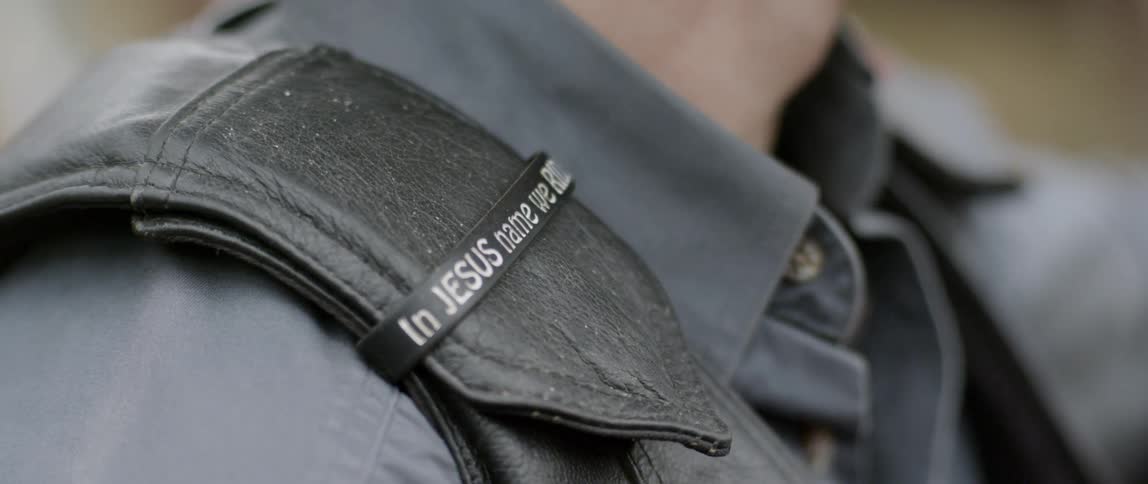 A man is wearing a band with a phrase on it on his shoulder