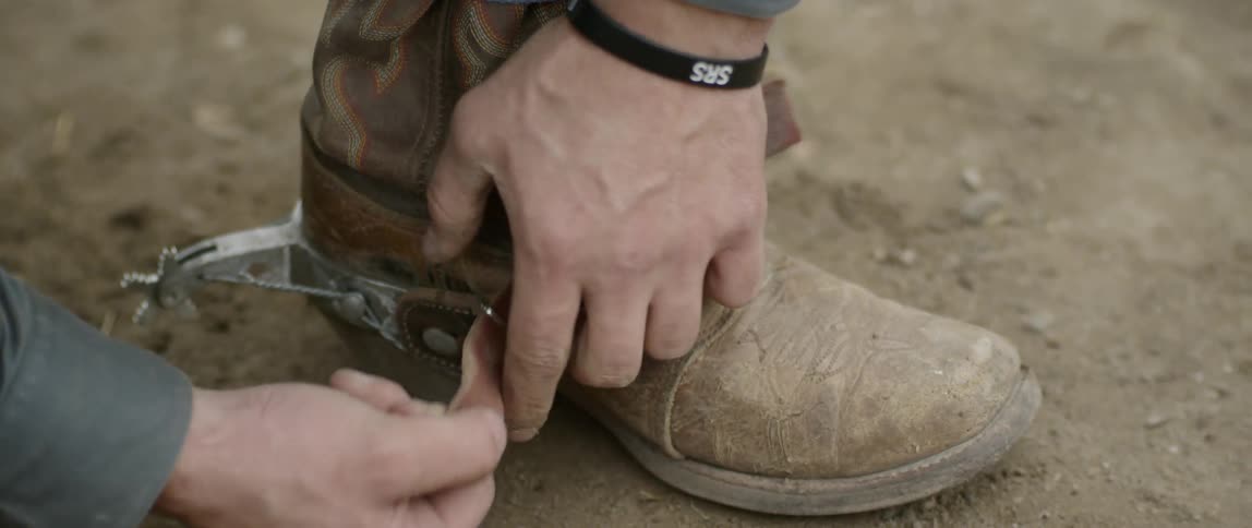 A cowboy secures the strap on his boot