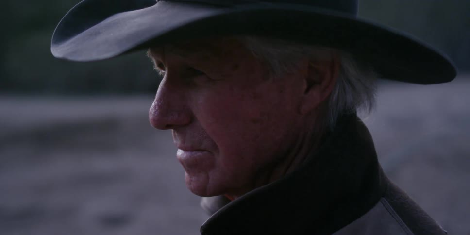 A cowboy stands outside on a ranch