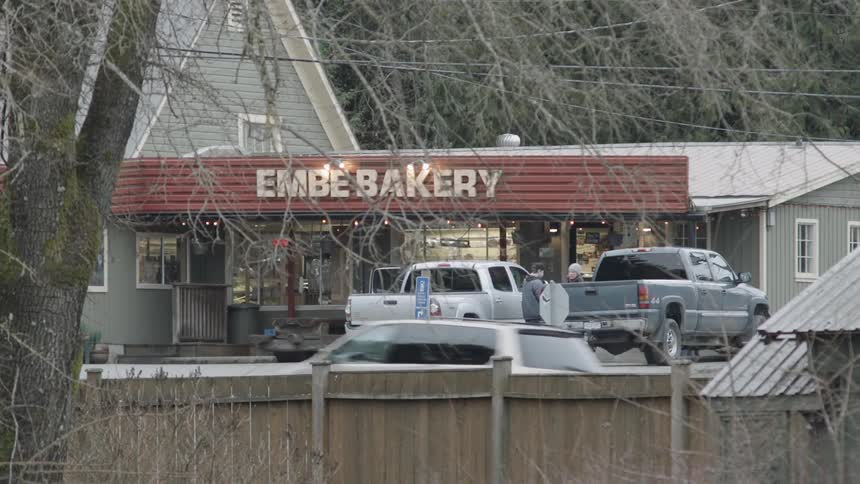 A couple are getting into their pickup truck outside a bakery during the day