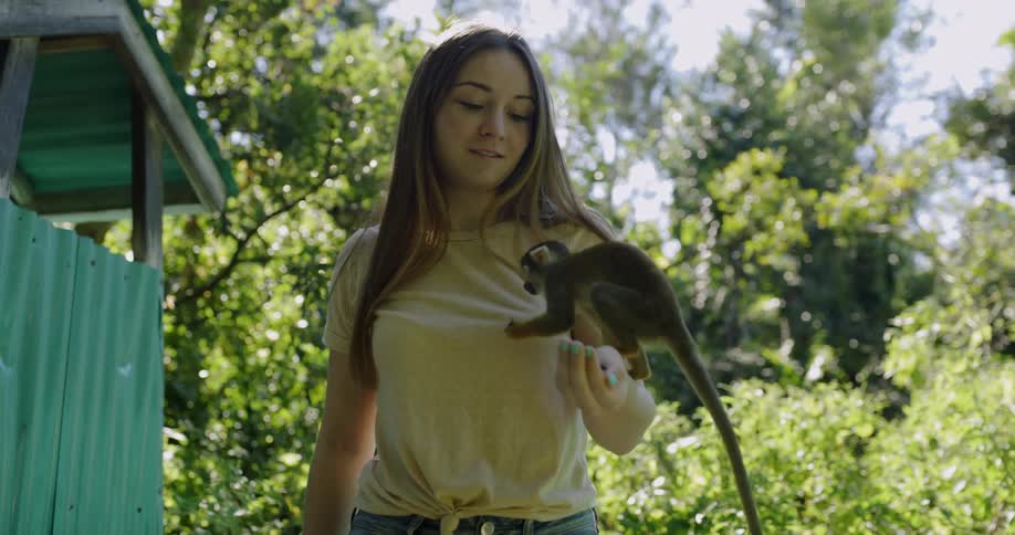 A woman holds a monkey while it eats from her palm