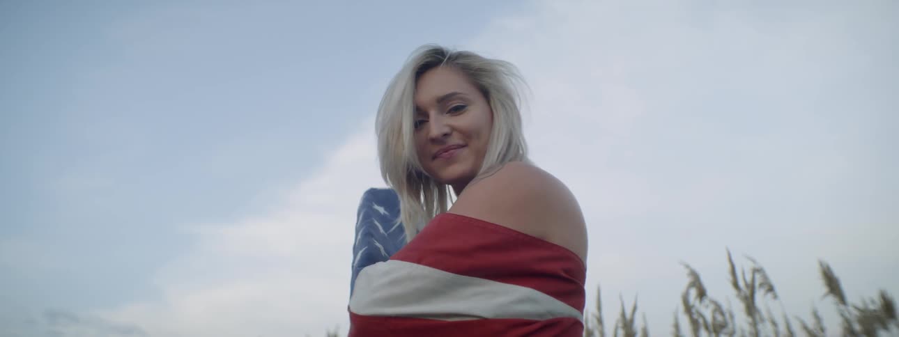 A woman smiles and wraps herself in an american flag