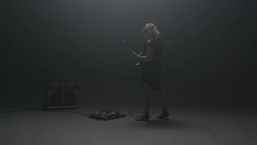 A woman is dancing and playing the guitar