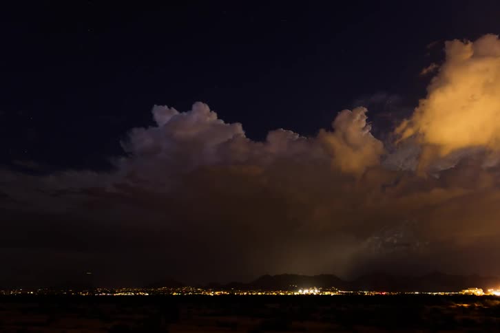Storm clouds and lightning over city lights