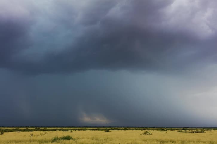 The storm clouds move engulfing the field ahead