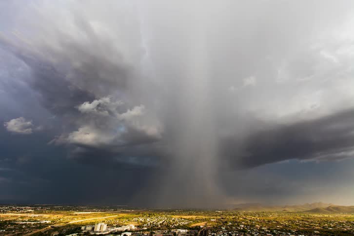 Rain falls from clouds in a rural field