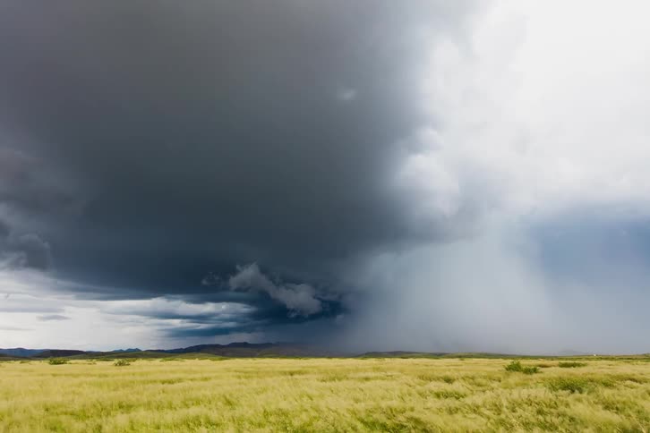 A storm is blowing across a prairie in daylight