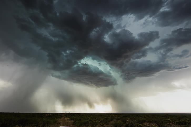 A storm is moving across a plain and dropping rain in daylight