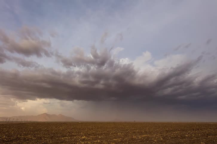 Storm clouds are moving over a desert setting during the day