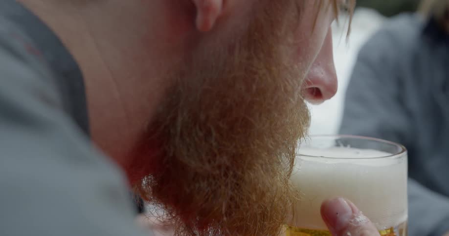 A man is taking a look at a beer he is drinking outside in winter