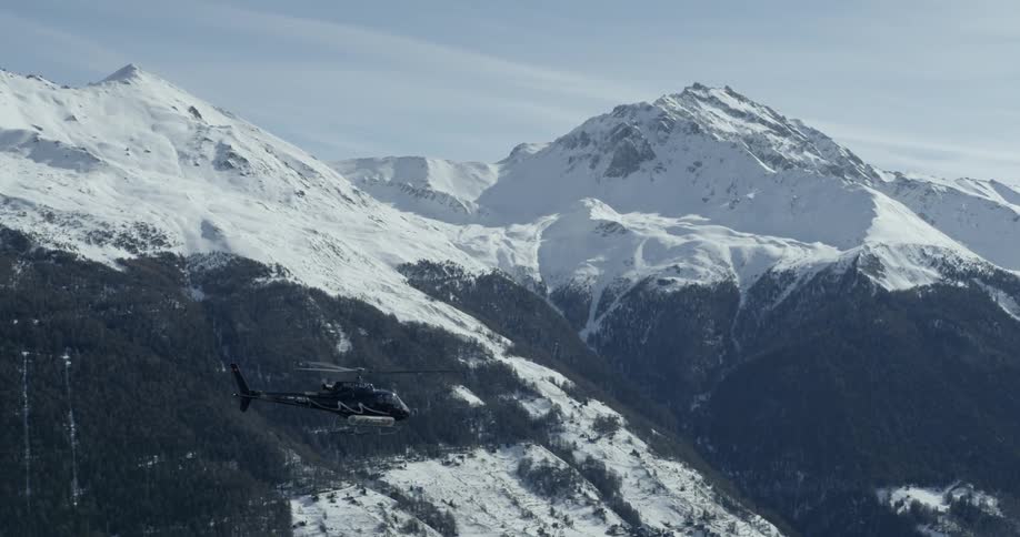 A helicopter flies high over the mountain