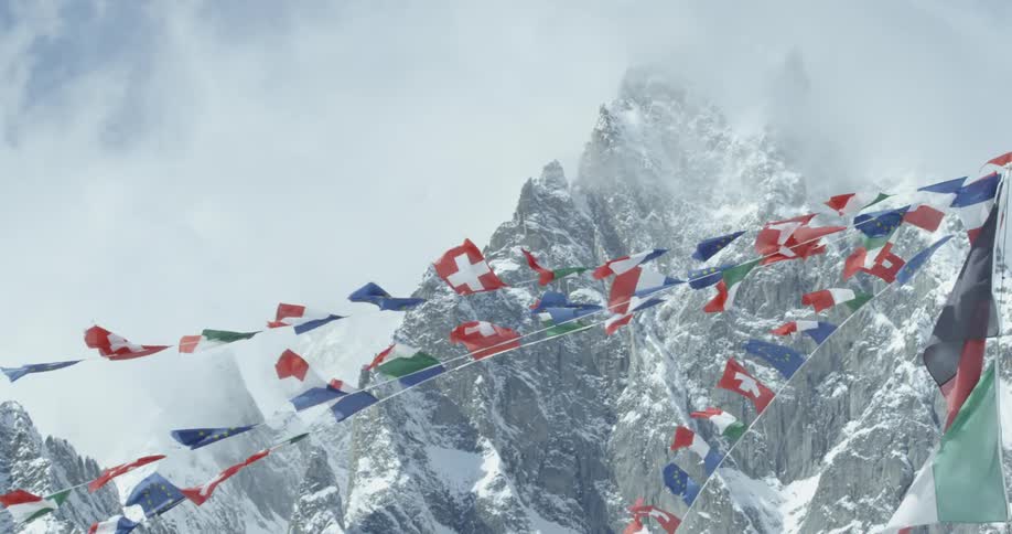 Flags are flapping in the breeze as they hang above a view of a mountain range