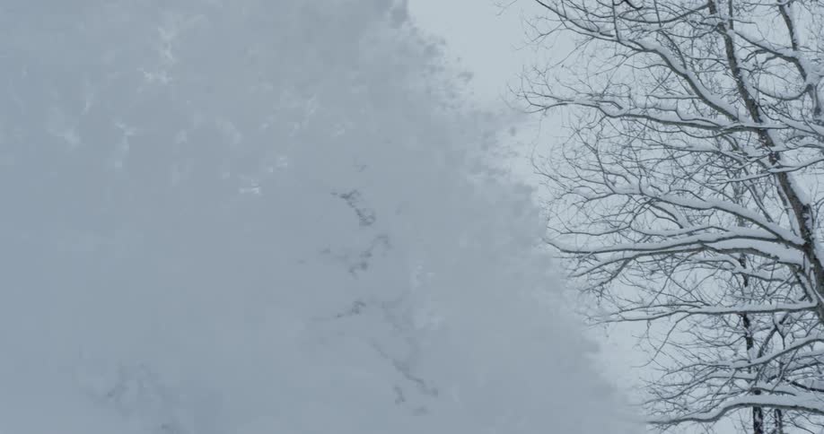 Snow flying as a snowboarder rides by on a cloudy day