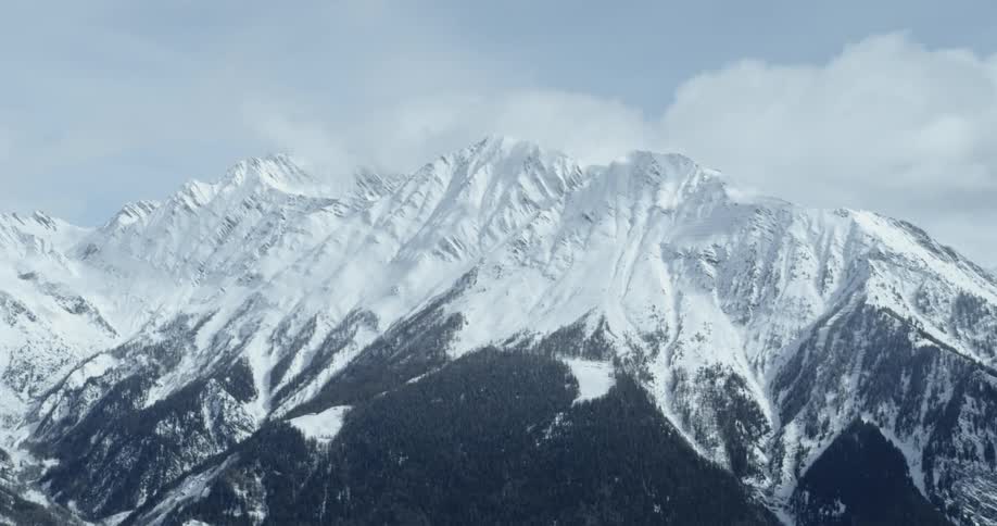 Clouds pass over snowy mountain peaks