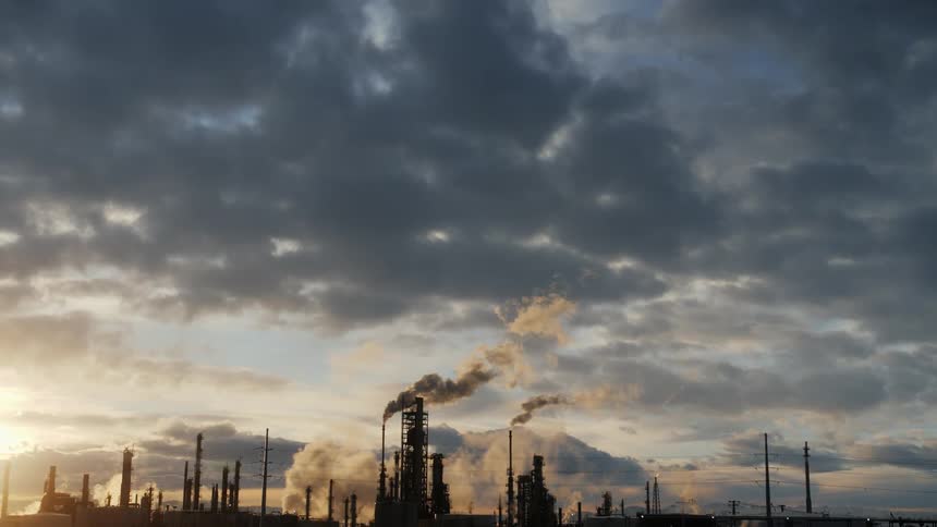 Smoke and steam billow from an industrial plant at dawn
