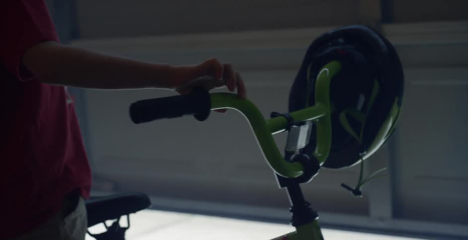 A young boy rubs a green bicycle in a garage