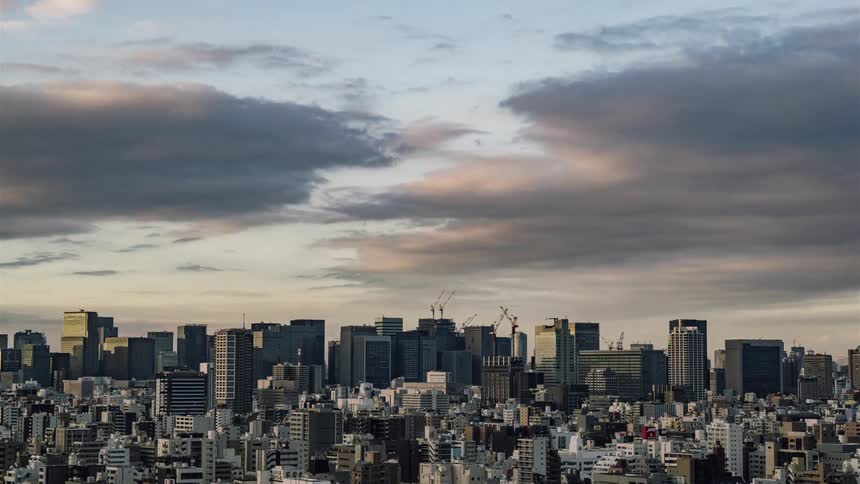Clouds roll over a large city at sunset