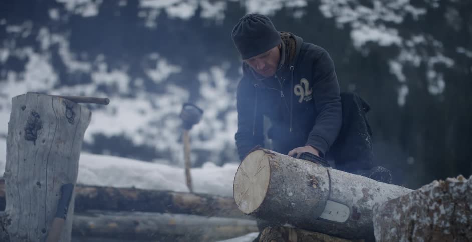 Man cuts through a log with a chainsaw