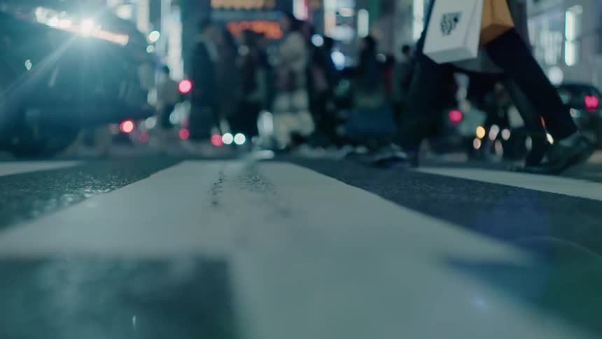 People and cars in a city cross an intersection at night