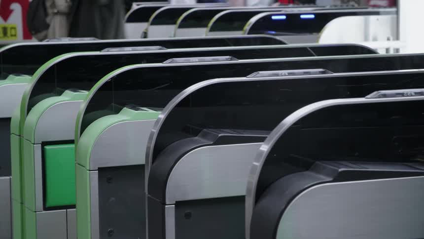People are moving through turnstiles in a station