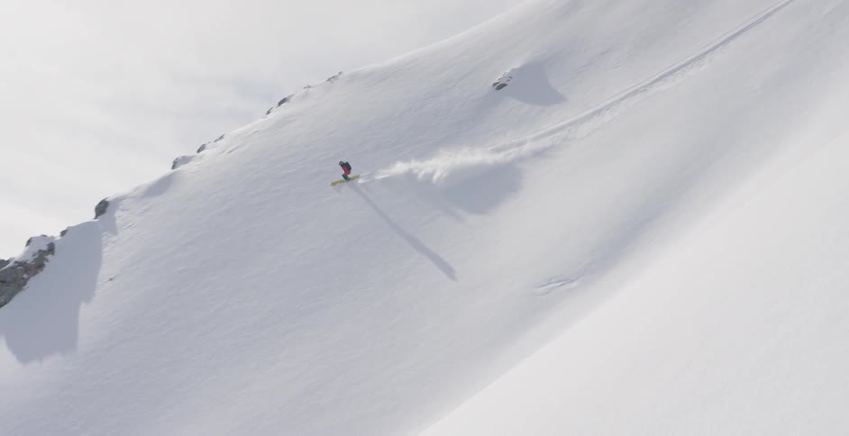 A skier is skiing down a mountainside during the day