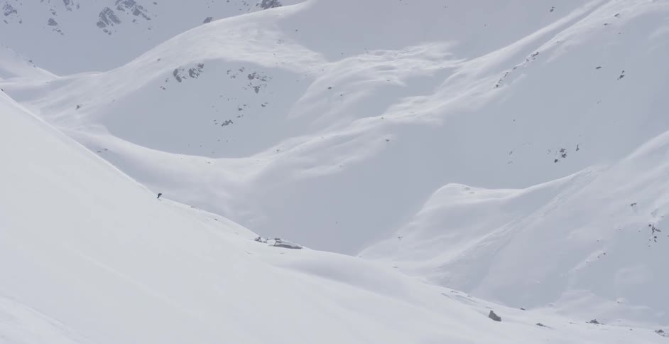 A skier moves down a steep mountain