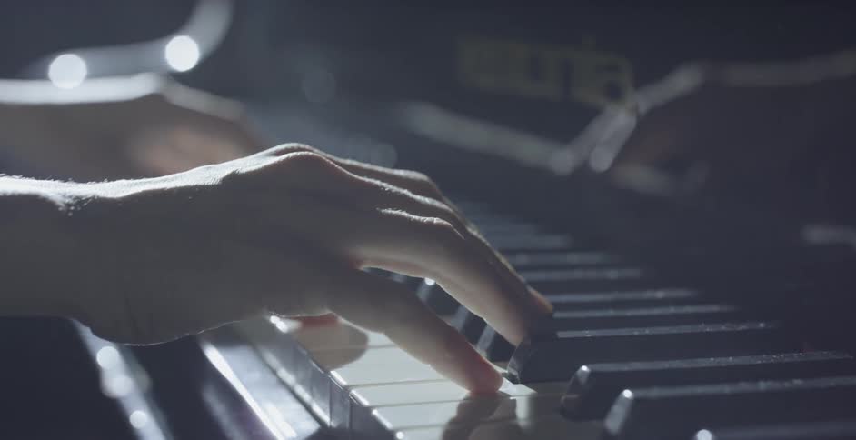 A person puts their hands on the piano keys and begins playing