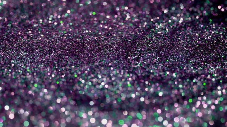 Purple glitter drifts in a liquid and refracts light