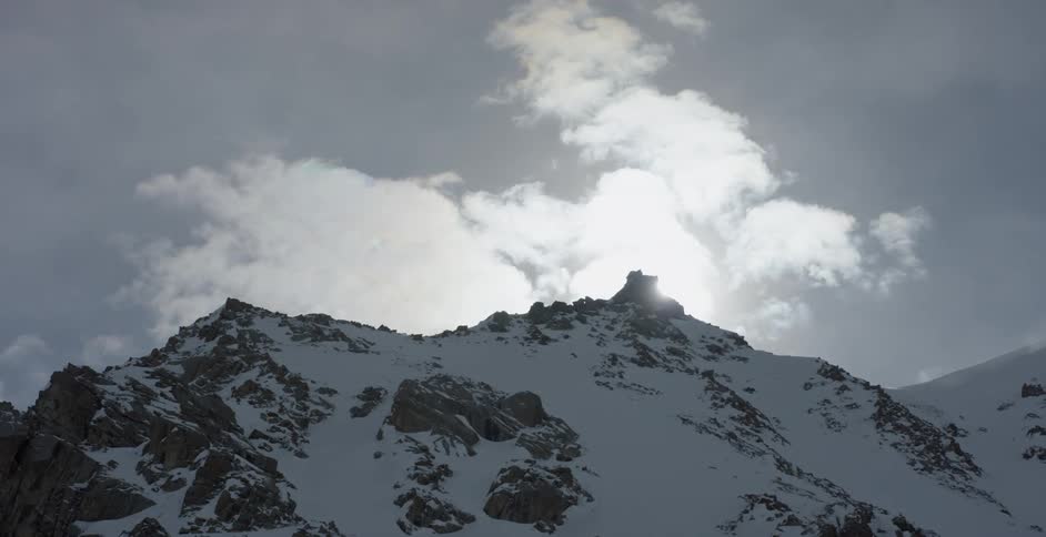 Clouds pass above a snowy mountain