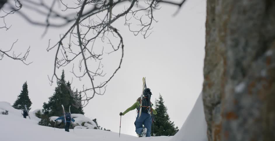 A skier hikes up a snowy mountainside
