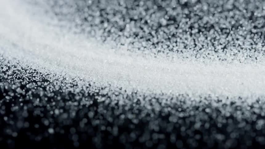 White granules vibrate on a black surface