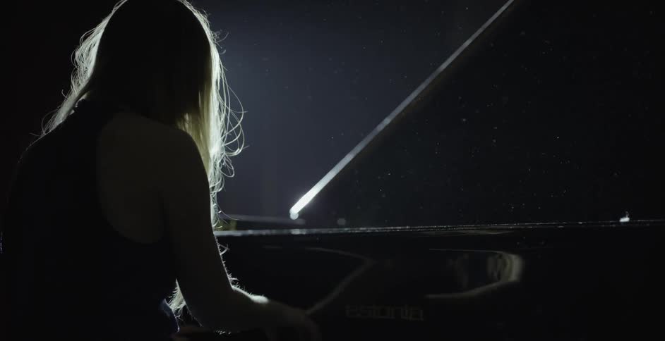 A woman is playing a piano inside on a stage
