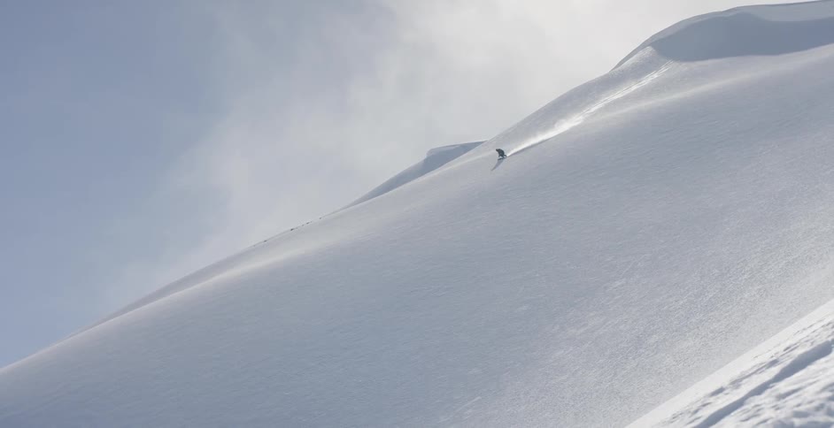 A person is skiing down the slope on a sunny day