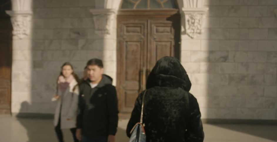 A person walks over to the buildings and enters the large wooden door