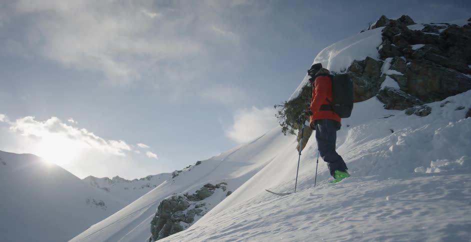 A skier looks out from atop a snowy mountain