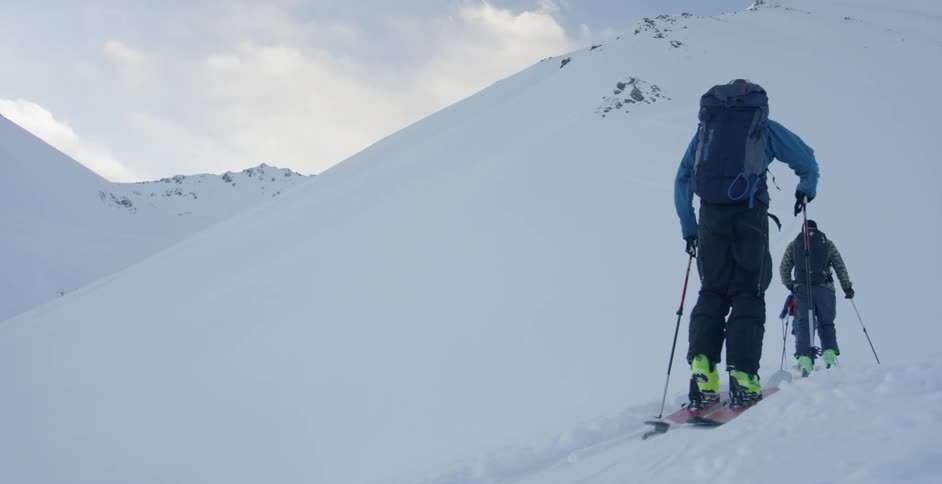 Three people climb up a snowy mountain on skis