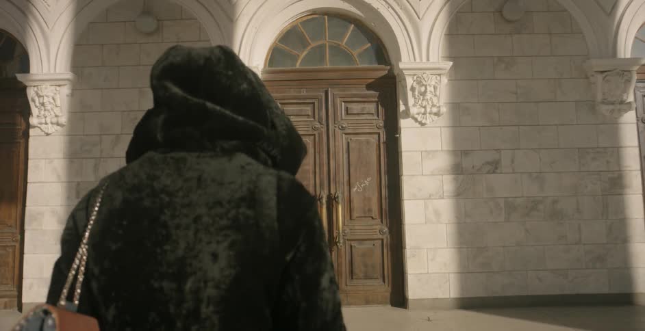 Someone walks towards a double door on a bright day