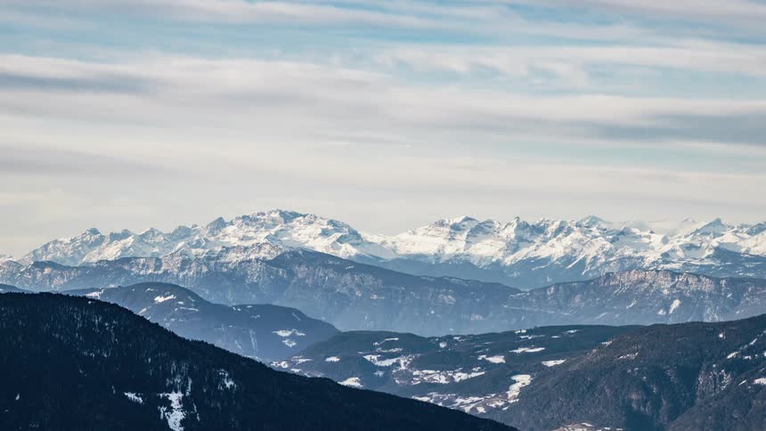 Clouds float over snowy mountains