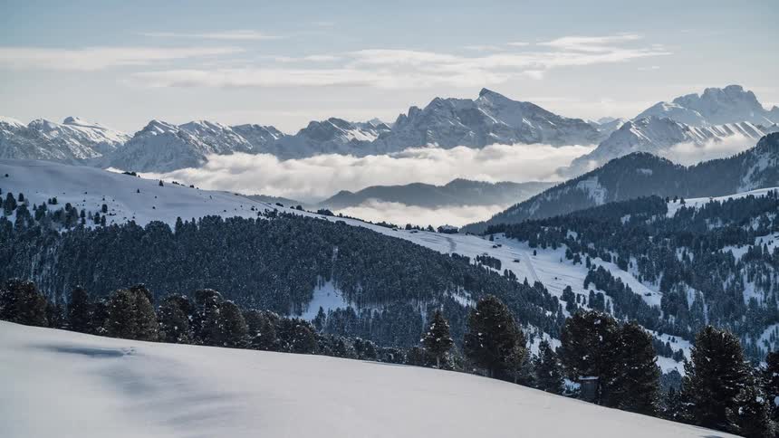 Clouds float over snowy mountains