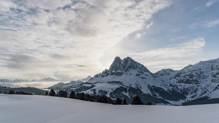 Clouds float over a snowy mountain range