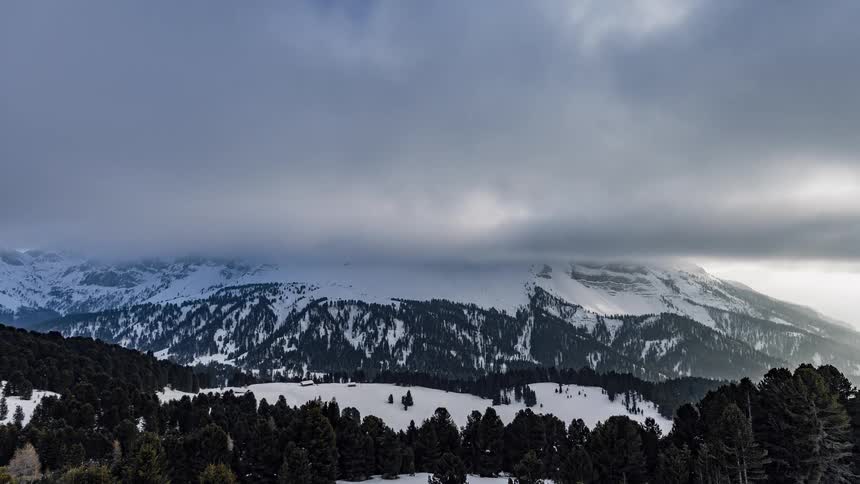 Clouds roll over snowy mountains